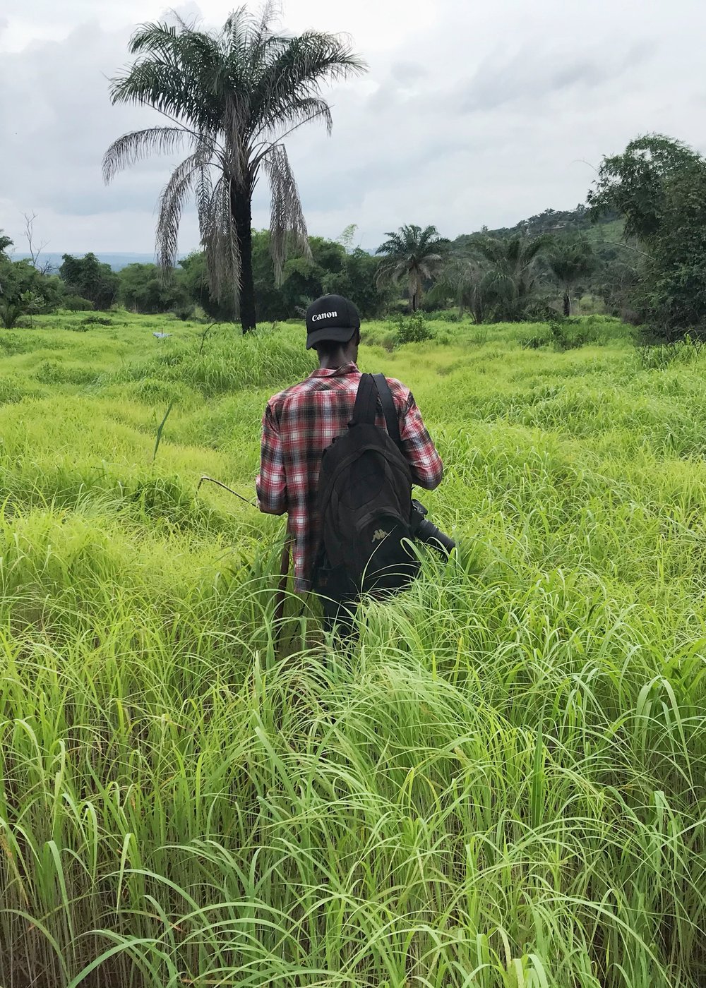 Emeka Mbaebie walking through tall grass in the field with camera