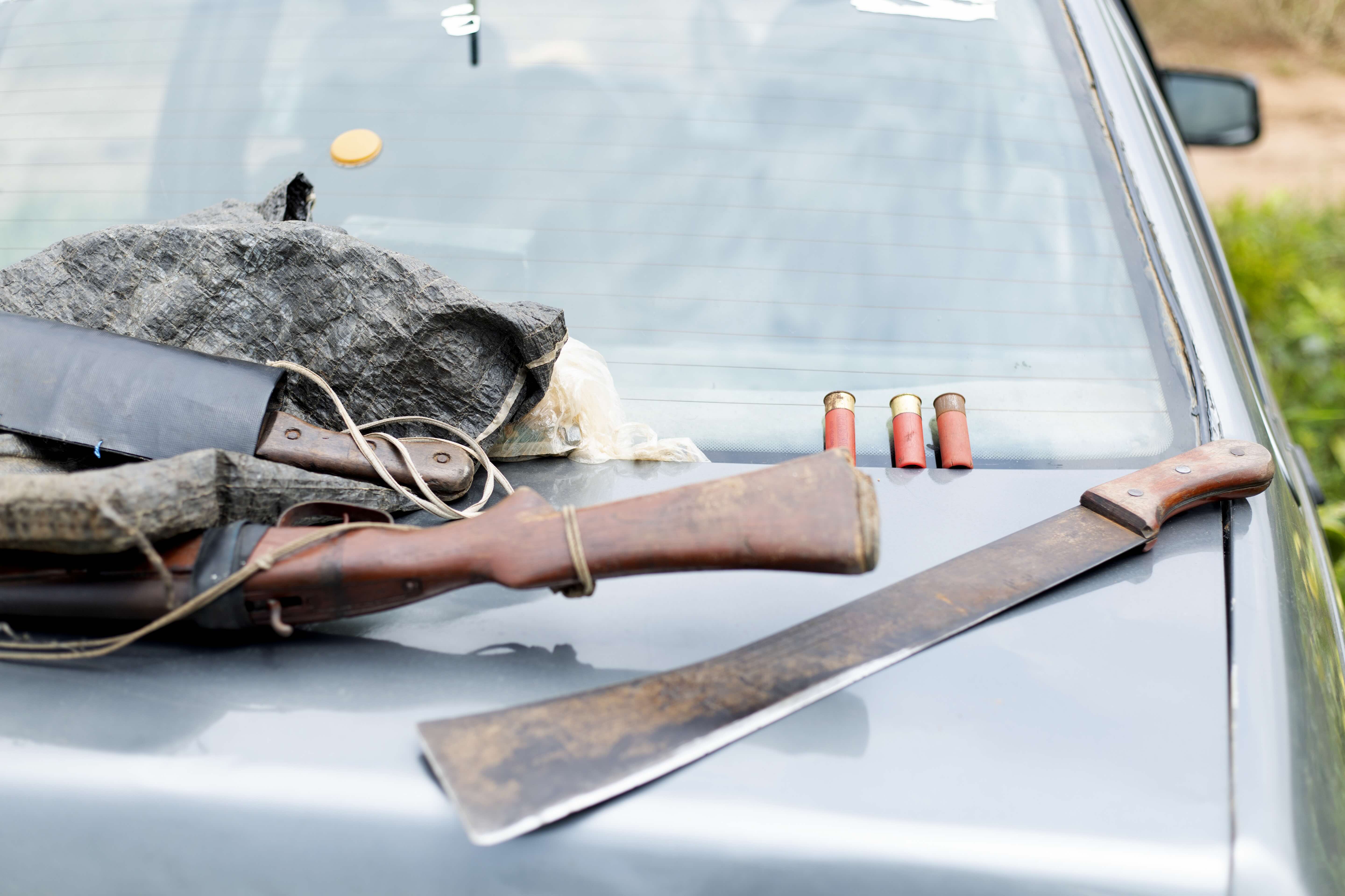 Rifle, machete and ammunition laid on car bonnet